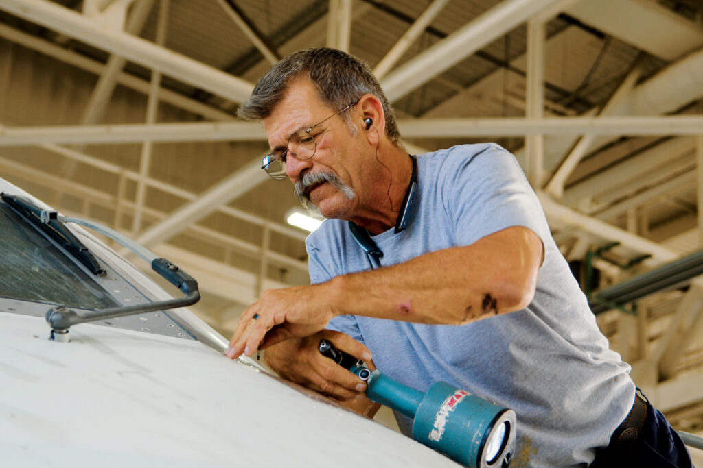 A man sitting and working on the nose of the CRJ-550